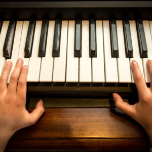 Closeup photo of child's hands playing on the piano