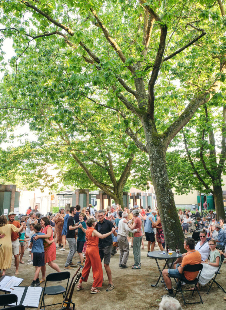 foto folkbal mensen dansen onder bomen op binnenplaats Academie